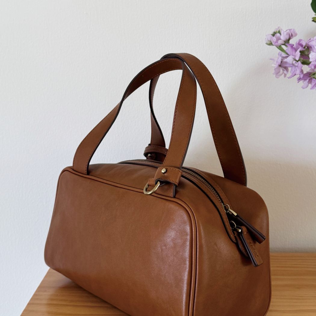 Lifestyle view of AUSTRALIAN SHEPHERD® Dunelight Leather Barrel Crossbody Bag ASA 065 in Chestnut with elegant barrel shape and leather handles.